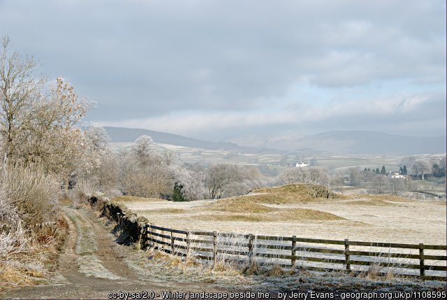 Frosty country lane in winter with distant hills